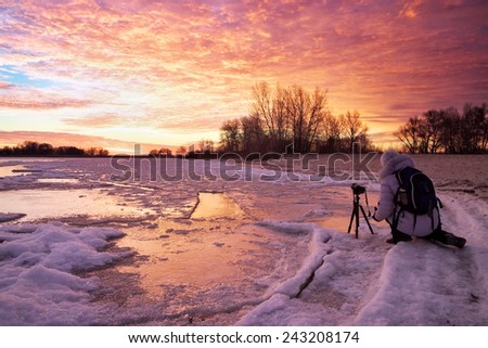 Photographer take pictures on the river bank in winter. Girl, photographed sunset