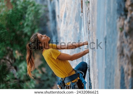 The girl climbs the rock. The climber trains on natural terrain. Extreme sport. Outdoor activities. A woman overcomes a difficult route rock climbing.
