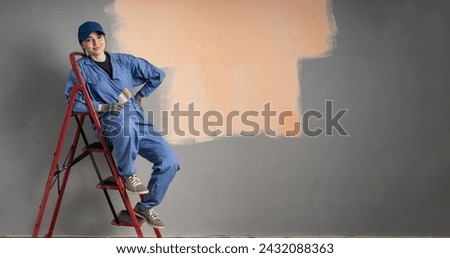 Beautiful young woman sitting on ladder doing wall painting and looking at camera. Space for text. Banner