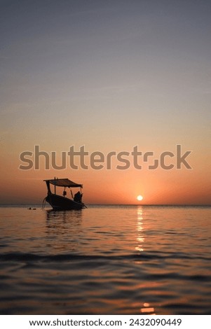 Sunset in Ko Lanta, Thailand. The picture was taken in January 2024. A lonely fishing boat lies in front of the red sunset.