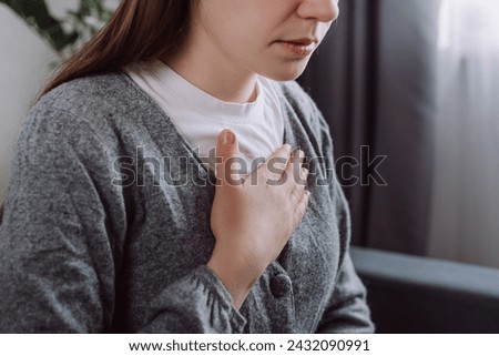 Close up of ill sad young caucasian woman putting hand on chest, feels discomfort. Having pain in chest, Gastroesophageal Reflux Disease have frequent belching. Healthcare medical and people concept Royalty-Free Stock Photo #2432090991