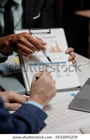 Three businesspeople are brainstorming together in a conference room about documents that need to be edited on the table, Colleagues are exchanging ideas about business strategies.