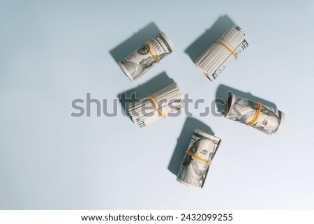 Tubes of hundred dollar bills rewound with an elastic band on a light background. High quality photo