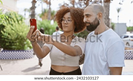 Beautiful couple making love-filled selfie together with smartphone in sunlit park