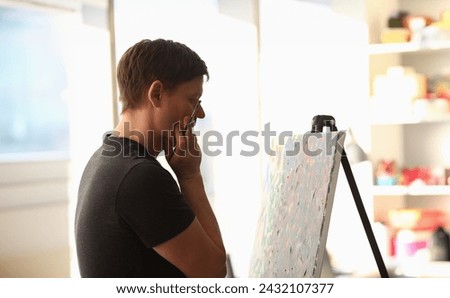 Portrait of talented young man creating masterpiece. Artist thinking on idea for painting and holding paintbrush. Work as hobby. Art and creativity concept
