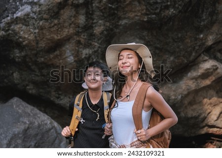 An Asian couple spent their vacation hiking along nature trail, visiting waterfall and enjoying forest views together.