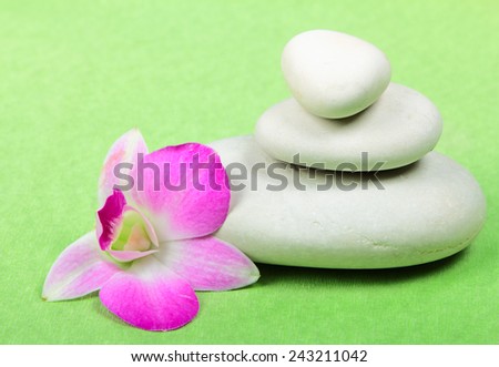 Pyramid of the stones with orchid on green background