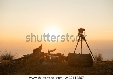 Professional Photographer with lens telephoto lenses on tripod at top of mountain during morning sunrise gold sunlight sky.