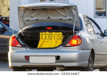 Opened Car Trunk With Yellow Food Delivery Bag Inside