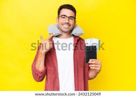 Young handsome man with Inflatable Travel Pillow over isolated yellow background giving a thumbs up gesture Royalty-Free Stock Photo #2432125049