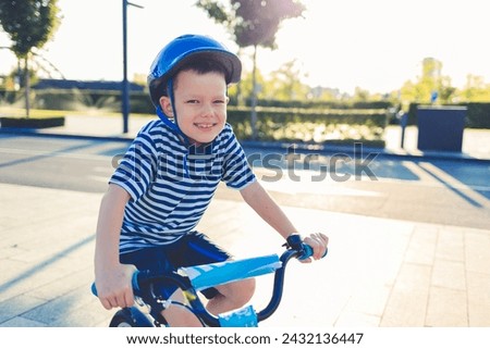 Happy kid boy, having fun in park with a bicycle on beautiful sunny day. Active child wearing bike helmet. Healthy happy child having fun with cycling on bike. Active leisure for children. 