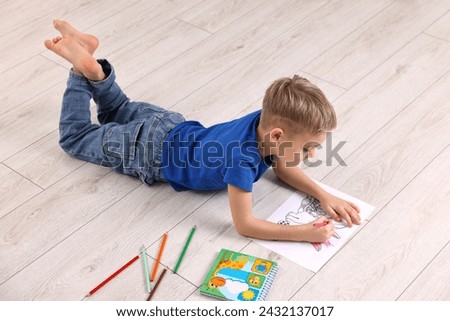 Cute little boy drawing on warm floor at home. Heating system