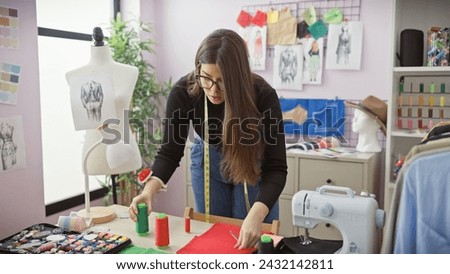 A focused woman tailor measuring fabric in a colorful atelier surrounded by sewing equipment and mannequins.
