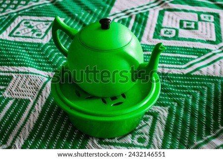 A green plastic tea pot sitting on top of saucer