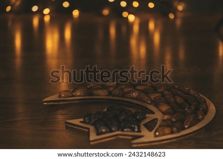 Dried dates on a wooden tray in the shape of a month and moon on a wooden background with glittering golden bokeh lights. Muslim holy month Ramadan Kareem. Dark background. Soft focus. Shallow DOF.