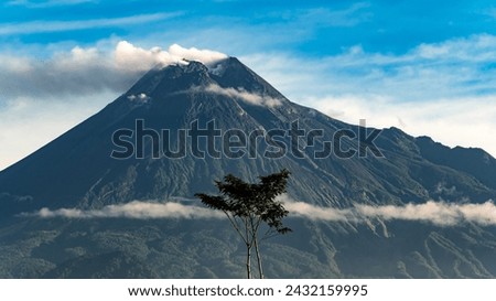 Beautiful Merapi Volcano landscape view with detail peak small eruption and cloudy blue sky background. Shot from south side in the morning