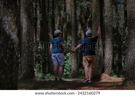 A woman and a man hold hands while exploring the forest 