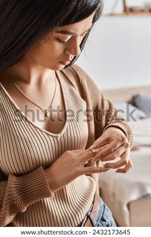 young asian woman taking off wedding ring in sign of divorce, relationship difficulties concept Royalty-Free Stock Photo #2432173645