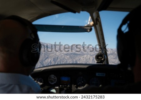 Two Pilots Flying Over Mountainous Terrain Royalty-Free Stock Photo #2432175283