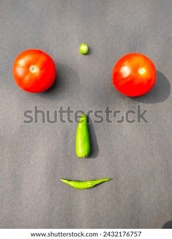 Human face created using tomatoes and green chillies on a black background simple installation artwork ultrahd hi-res jpg stock image photo picture selective focus vertical background top ankle view 