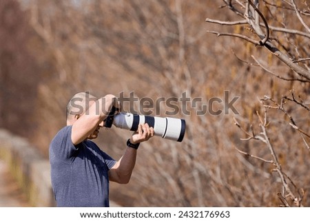 Wildlife and nature photographer in the forest, with camera and long tele lens attached