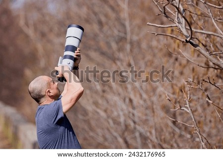 Wildlife and nature photographer in the forest, with camera and long tele lens attached