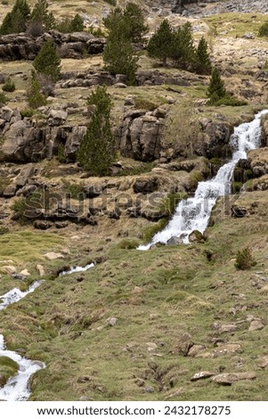 serene landscape with a cascading waterfall, rocky terrain, sparse green vegetation, and a cloudy sky