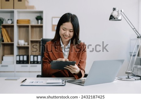 Businesswomen using tablet with laptop and document on desk in modern office with virtual interface graphic icons network diagram.