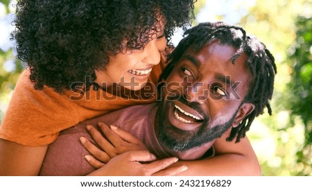 Loving Mid Adult Couple Outdoors In Summer Garden Or Countryside With Man Giving Woman Piggyback