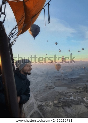 Boy flying in a hot air balloon with more hot air balloons in the background in goreme turkey