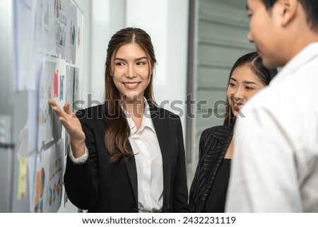 Dynamic businesswoman actively engages with her colleagues, presenting and explaining concepts on a storyboard in a corporate setting. Royalty-Free Stock Photo #2432231119