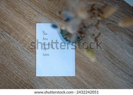 You are worth of love. Birds eye view of handwritten message affirming positively to someone who feels unworthy. Notelet on a desk. Simple design. Kindness and hope for healing mental health.  Royalty-Free Stock Photo #2432242051