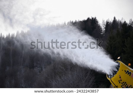 artificial snow cannon in action on the ski slopes
