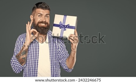 mature bearded guy with present box on grey background. ok