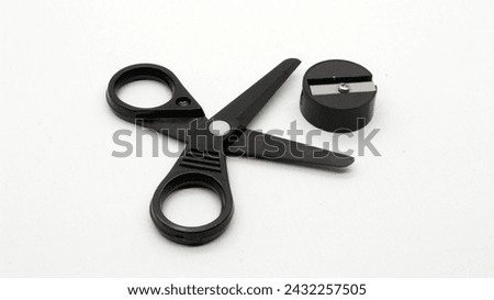 Black scissors with and black pencil sharpener a small size on a white background.