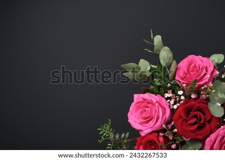 Holiday composition with bouquet of red and pink roses on black background. Space for your text.