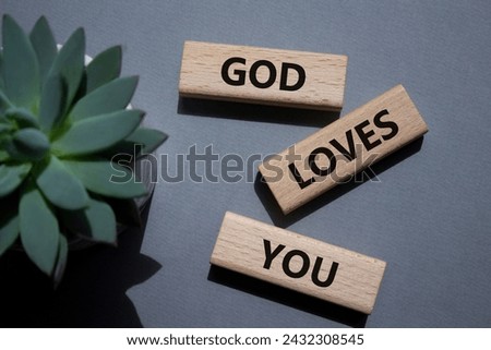 God loves you symbol. Wooden blocks with words God loves you. Beautiful grey background with succulent plant. Religion and God loves you concept. Copy space.