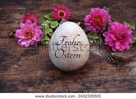 Happy Easter: Inscribed Easter egg with flowers and chicken feathers on wooden background. German inscription translated means Happy Easter. Royalty-Free Stock Photo #2432320503