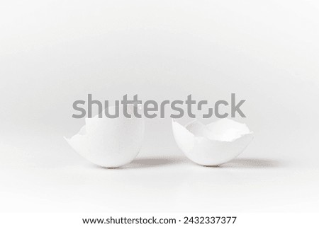 Close up of white broken chicken egg shells against white background. Front view. Royalty-Free Stock Photo #2432337377