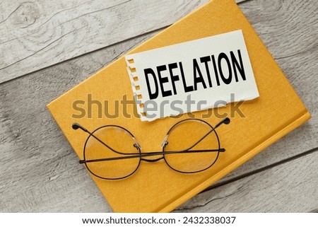 deflation symbol. torn paper on a yellow notepad on a wooden table. words