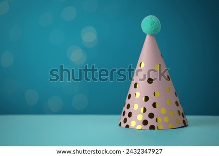 Pink party hat on light blue background, space for text