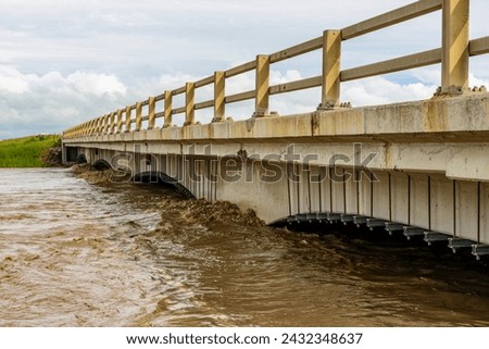 Rising flood waters from the Highwood River threaten a bridge on Highway 2 in southern Alberta in June, 2013. Royalty-Free Stock Photo #2432348637