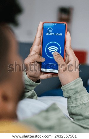Close-up view of young man connecting smart phone to wifi at home. Technology concept. Vertical photo.