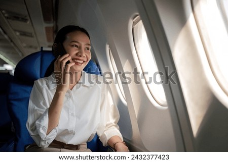 Smiling Asian woman enjoying a comfortable flight while sitting in an airplane cabin There is wireless internet on the plane. Passengers near the window.