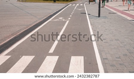A sign of a bicycle path and pedestrian crossing on the asphalt in a city park, close-up