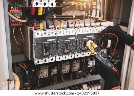 Electricity and electrical safety maintenance service system, Technician hand checking electric current voltage at circuit breaker terminal and cable wiring in main power distribution board. Royalty-Free Stock Photo #2432395837
