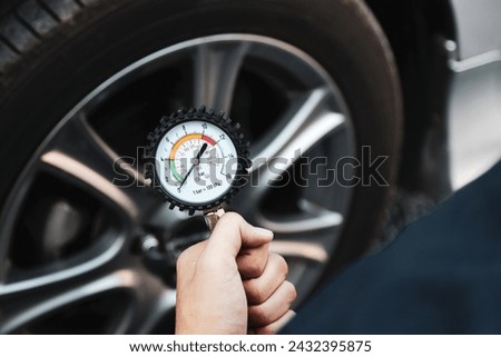 Hand car mechanic holding car tire pressure check equipment tool to checking low tire pressure inflating tires to or refill or air inflate to safety and car care service maintenance inspection. Royalty-Free Stock Photo #2432395875