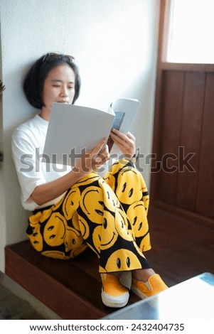 Close up teenage girl holding and reading book or magazine in reading room at home, copy space concept.