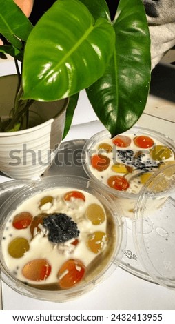 Jelly balls filled with fruit with milk cheese sauce in a bowl on a white background.
