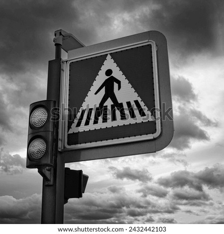 Black and White Crosswalk Road Sign with Dark Clouds in the Background

